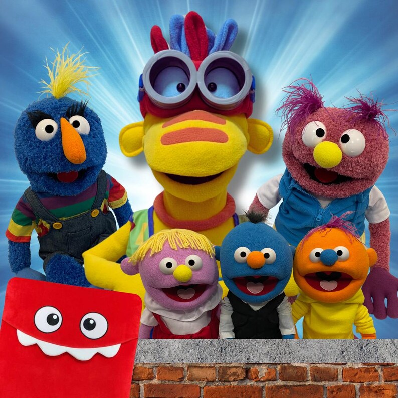 May include: A group of colorful puppets with different facial expressions. The puppets are standing in front of a brick wall. The puppets are wearing various outfits, including a blue shirt, a yellow shirt, a red shirt, and a purple shirt.