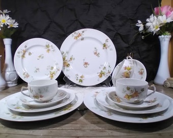 May include: A set of white porcelain teacups and saucers with a delicate floral pattern featuring green leaves and orange and yellow flowers. The set includes two teacups, two saucers, two teacups with saucers, and two larger plates.