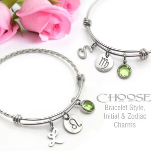 May include: Two silver bangle bracelets with charms. One bracelet has a braided design and the other is a simple circle. Both bracelets have a green gemstone charm, a zodiac sign charm, and an initial charm. The text on the image reads "CHOOSE: Bracelet Style, Initial & Zodiac Charms".