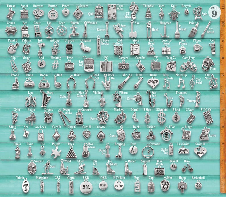 Puede incluir: Una colecci&oacute;n de dijes de metal plateado dispuestos en una cuadr&iacute;cula sobre un fondo azul claro, con diversas formas como instrumentos musicales, equipos deportivos y herramientas. Una regla de madera a la derecha muestra 25 cm.