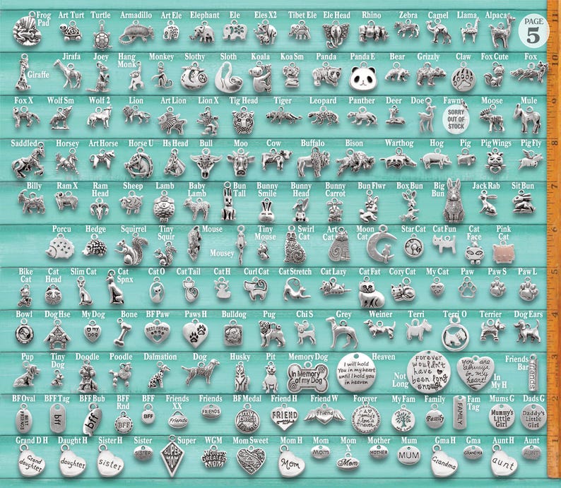 May include: A collection of silver-toned metal charms featuring various animal, pet, and family-themed designs arranged in rows on a light blue background, with a vertical orange ruler on the right side showing measurements in inches.