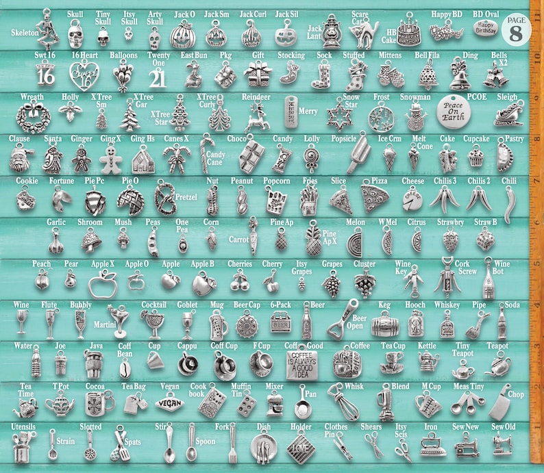 May include: A collection of silver-toned metal charms arranged in a grid on a teal background, featuring various shapes including food, holiday symbols, and household items, with a vertical ruler on the right side showing 10 inches of length.