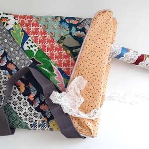 Peut inclure: Un sac pour ordinateur portable en tissu patchwork avec une bandoulière grise et une pochette zippée assortie. Le sac présente une variété de motifs colorés et est fabriqué dans un tissu doux et résistant.