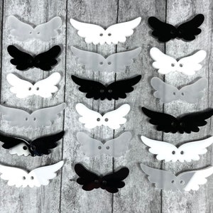 May include: Assortment of 10 pairs of angel wings in white and black. The wings are made of plastic and have a two-dimensional shape.