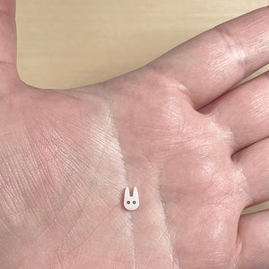 May include: A small white plastic bunny charm with two black dots for eyes.