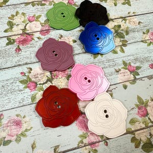 May include: Assortment of six rose-shaped buttons in various colors, including green, black, blue, purple, pink, and white.