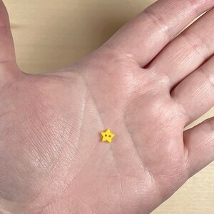 Peut inclure: Un petit bouton jaune en forme d'étoile avec deux trous.