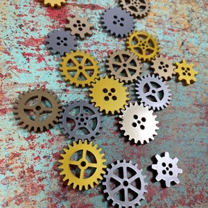 May include: A collection of gold and silver gears on a blue and brown textured background. The gears are of various sizes and are arranged in a random pattern.