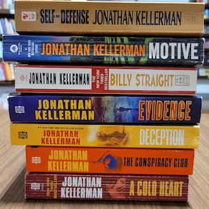 Könnte beinhalten: Ein Stapel von sieben Büchern von Jonathan Kellerman. Titel sind u.a. "Self-Defense", "Motive", "Billy Straight", "Evidence", "Deception", "The Conspiracy Club" und "A Cold Heart". Die Bücher sind in verschiedenen Farben gehalten, mit Text in Weiß und Gelb.
