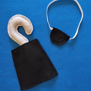 May include: A white felt pirate hook with a black felt sheath and a black felt eye patch with a white elastic band.