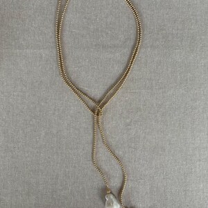 May include: A gold chain necklace with two large white pearl pendants.