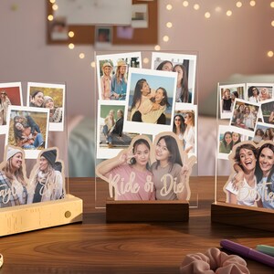 May include: Three clear acrylic photo display stands with wooden bases, each featuring multiple printed polaroid-style photos and custom text cutouts including "Taylor & Sky," "Ride & Die," and "Besties" layered over the images.