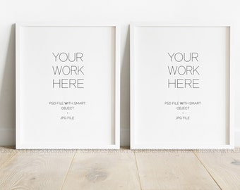 May include: Two white framed art prints with the text "YOUR WORK HERE". The prints are displayed against a white wall and rest on a light wood floor. The text "PSD FILE WITH SMART OBJECT + JPG FILE" is below the main text.