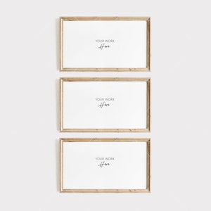 Op de afbeelding: Drie rechthoekige houten fotolijsten met witte interieurs worden verticaal weergegeven. Elke lijst heeft een lichte, natuurlijke houtnerf. De tekst "YOUR WORK Here" is in cursieve letters in het midden van elk frame geschreven.