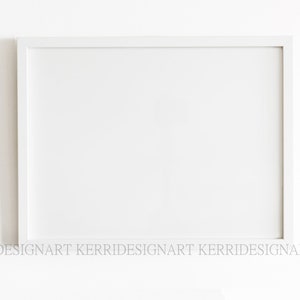 May include: A white picture frame with a white mount. The frame is on a white wall.