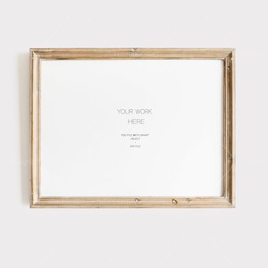 May include: A rectangular, light-colored wooden picture frame with a white interior. The frame has a distressed, vintage look. Text on the white interior reads "YOUR WORK HERE" and other smaller text below. The frame is set against a plain white background.