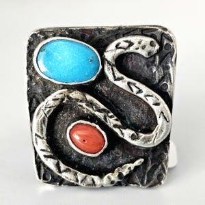 May include: A silver ring with a turquoise and coral stone inlay. The ring features a stylized snake design.