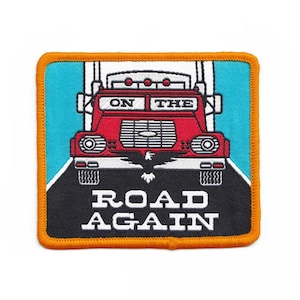 May include: A red and white truck with the words "On The Road Again" on a black background. The truck is driving on a blue road. The patch is surrounded by an orange border.