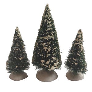 May include: A set of three miniature bottle brush trees in varying heights, featuring dark green bristles with white flocking to simulate snow. Each tree is mounted on a round, white, textured base, creating a winter-themed decorative display.
