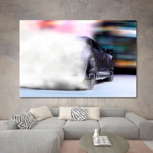 May include: A black sports car with smoke coming from the rear tires, driving on a white surface with a blurred background.