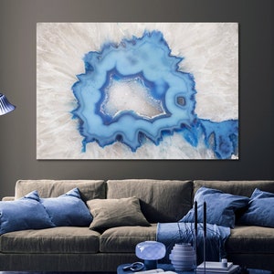 Puede incluir: Primer plano de una geoda de ágata azul y blanca sobre un fondo blanco. La geoda tiene una gran cavidad central llena de cristales azules.