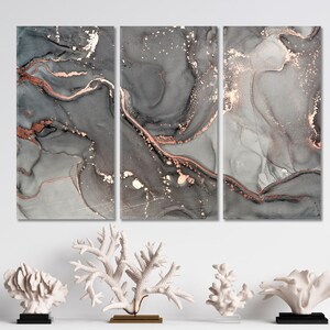 K&ouml;nnte beinhalten: Dreiteiliges abstraktes Kunstdruck-Set mit einem grauen und wei&szlig;en Marmorhintergrund mit ros&eacute;goldenen Akzenten. Die Drucke sind perfekt, um jedem Raum einen Hauch von moderner Eleganz zu verleihen.