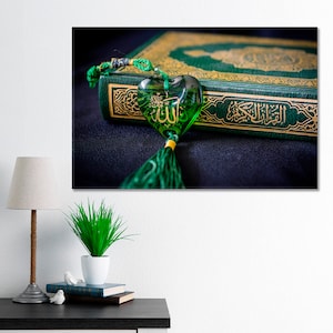 May include: A green book with gold lettering and a green heart-shaped charm with the word "Allah" written in Arabic script.