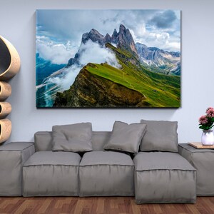 Puede incluir: Una fotografía panorámica de una cordillera con un sendero sinuoso que lleva a la cima. Las montañas están cubiertas de hierba verde y nubes. El cielo es azul con nubes blancas.