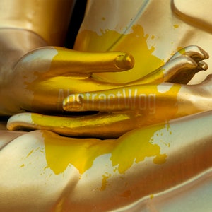 May include: Close-up of a golden statue's hands in a prayer position. The statue is covered in yellow paint splatters.