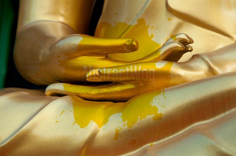 May include: Close-up of a golden statue's hands in a prayer position. The statue is covered in yellow paint splatters.