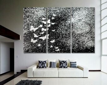 May include: A black and white triptych canvas wall art featuring a flock of white butterflies flying against a black background with a white speckled texture.