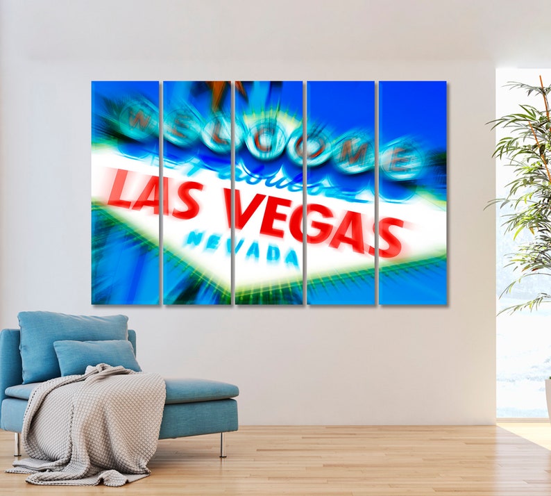 May include: A multi-panel canvas print featuring a close-up of the iconic "Welcome to Fabulous Las Vegas" sign with a blurred, motion-effect background. The sign is illuminated with bright red and white lettering against a blue sky.
