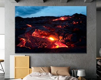 May include: A close-up of a lava flow with bright orange and red molten lava flowing through a field of black volcanic rock. The sky is a dark blue with a few clouds.