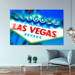 May include: A close-up of the iconic "Welcome to Fabulous Las Vegas" sign with a blue and white background. The sign is lit up with bright red and white lights. The sign is blurred and has a motion effect.