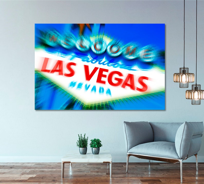 May include: A close-up of the iconic "Welcome to Fabulous Las Vegas" sign with a blue and white background. The sign is lit up with bright red and white lights. The sign is blurred and has a motion effect.