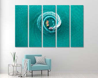 May include: An aerial view of a group of people on paddleboards forming a circle in turquoise water. The paddleboards are yellow and orange, and the water is clear and blue.