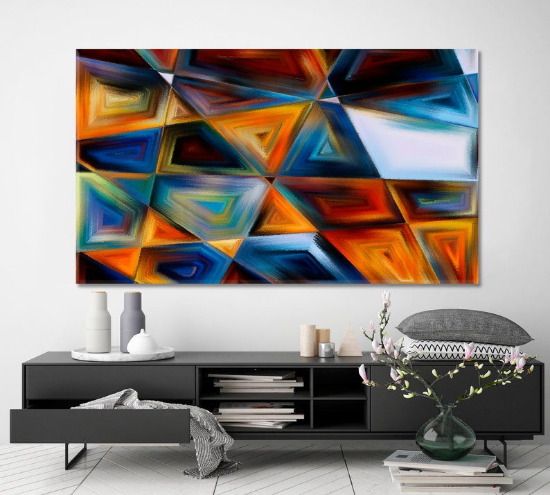 May include: Abstract painting featuring geometric shapes in shades of blue, orange, yellow, and brown. The painting is composed of overlapping triangles and squares.