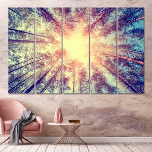May include: A multi-panel canvas print featuring a view of a forest from below, with the sun shining through the trees. The trees are tall and slender, with their branches reaching up towards the sky. The colors are muted and warm, creating a peaceful and serene atmosphere.