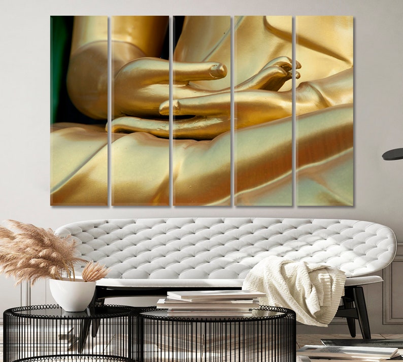 May include: Close-up of a golden Buddha statue's hands in a meditative pose. The statue is made of smooth, polished gold and the hands are folded together in a gesture of peace and tranquility.