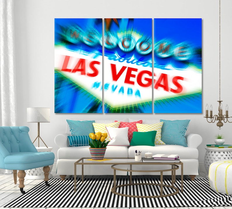 May include: A three-panel canvas print featuring a blurred image of the iconic "Welcome to Fabulous Las Vegas, Nevada" sign. The sign is illuminated with bright red and white lights against a blue sky.
