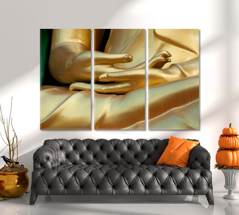 May include: A close-up of a golden Buddha statue's hands, with the fingers intertwined in a meditative pose. The statue is made of a smooth, shiny material, and the light reflects off its surface.