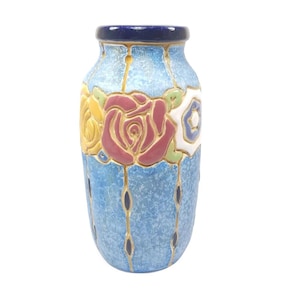 May include: A blue ceramic vase with a floral design. The vase has a textured surface and is decorated with yellow, red, green, and white flowers.