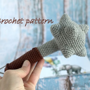 May include: Crochet pattern for a grey and brown toy hammer. The hammer has a star-shaped head and a brown handle.