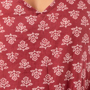 K&ouml;nnte beinhalten: Nahaufnahme eines roten Stoffes mit einem wei&szlig;en Blumenmuster. Der Stoff hat einen V-Ausschnitt und ist aus einem weichen, leichten Material gefertigt.