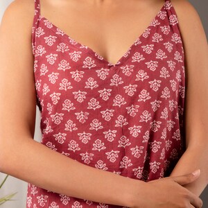 K&ouml;nnte beinhalten: Ein &auml;rmelloses, burgunderfarbenes Kleid mit wei&szlig;em Blumenmuster. Das Kleid hat einen V-Ausschnitt und d&uuml;nne Tr&auml;ger.