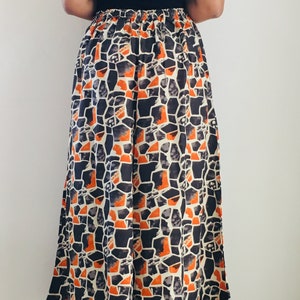 Puede incluir: Pantal&oacute;n de pierna ancha con un patr&oacute;n geom&eacute;trico en tonos naranja, negro y blanco. El pantal&oacute;n tiene una cintura con cord&oacute;n y una silueta fluida.