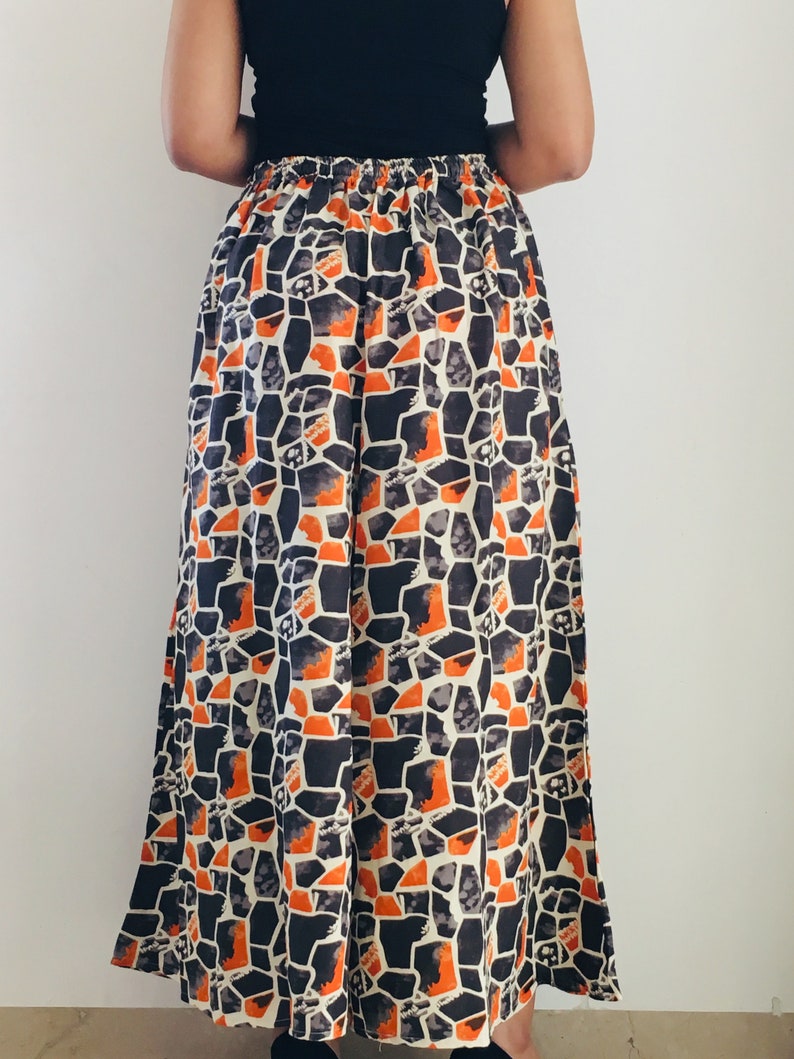 Puede incluir: Pantal&oacute;n de pierna ancha con un patr&oacute;n geom&eacute;trico en tonos naranja, negro y blanco. El pantal&oacute;n tiene una cintura con cord&oacute;n y una silueta fluida.