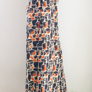 Puede incluir: Pantalones de pierna ancha con un patr&oacute;n geom&eacute;trico en tonos naranja, negro y blanco.