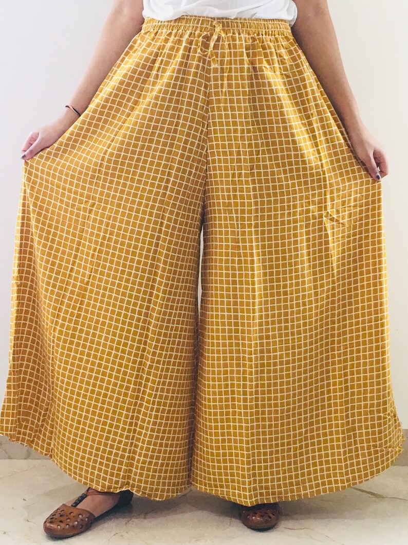 Puede incluir: Pantal&oacute;n de pierna ancha en color amarillo mostaza con estampado de cuadros blancos. El pantal&oacute;n tiene una cintura el&aacute;stica con cord&oacute;n.