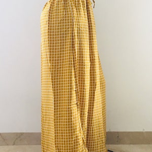 Puede incluir: Pantalones palazzo de color amarillo mostaza con estampado de cuadros blancos. Los pantalones tienen una cintura con cord&oacute;n y una pierna ancha.